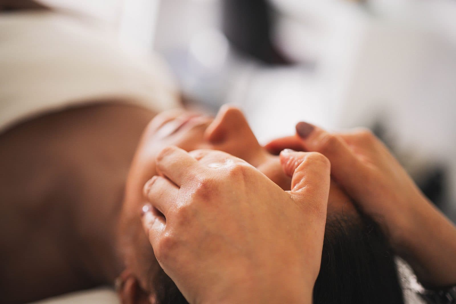 Focused myofascial massage along the jawline during a TMJ Facial